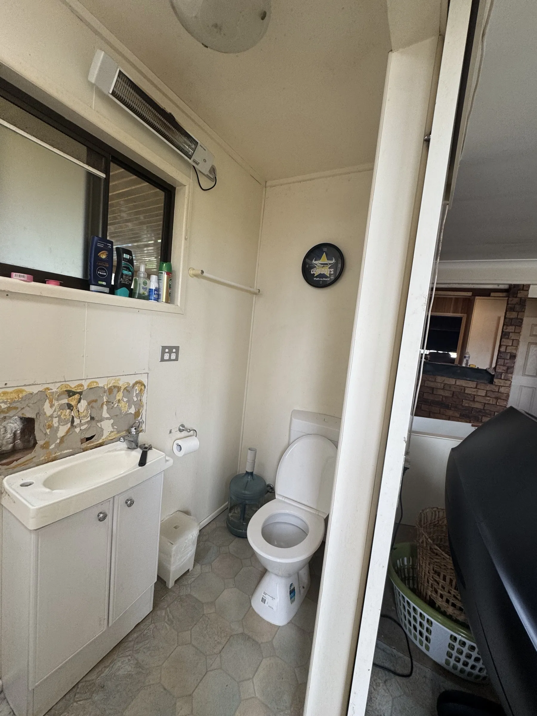 Before: original bathroom interior showing old ceramic tiles, dated fittings, and a built-in bathtub prior to the full renovation