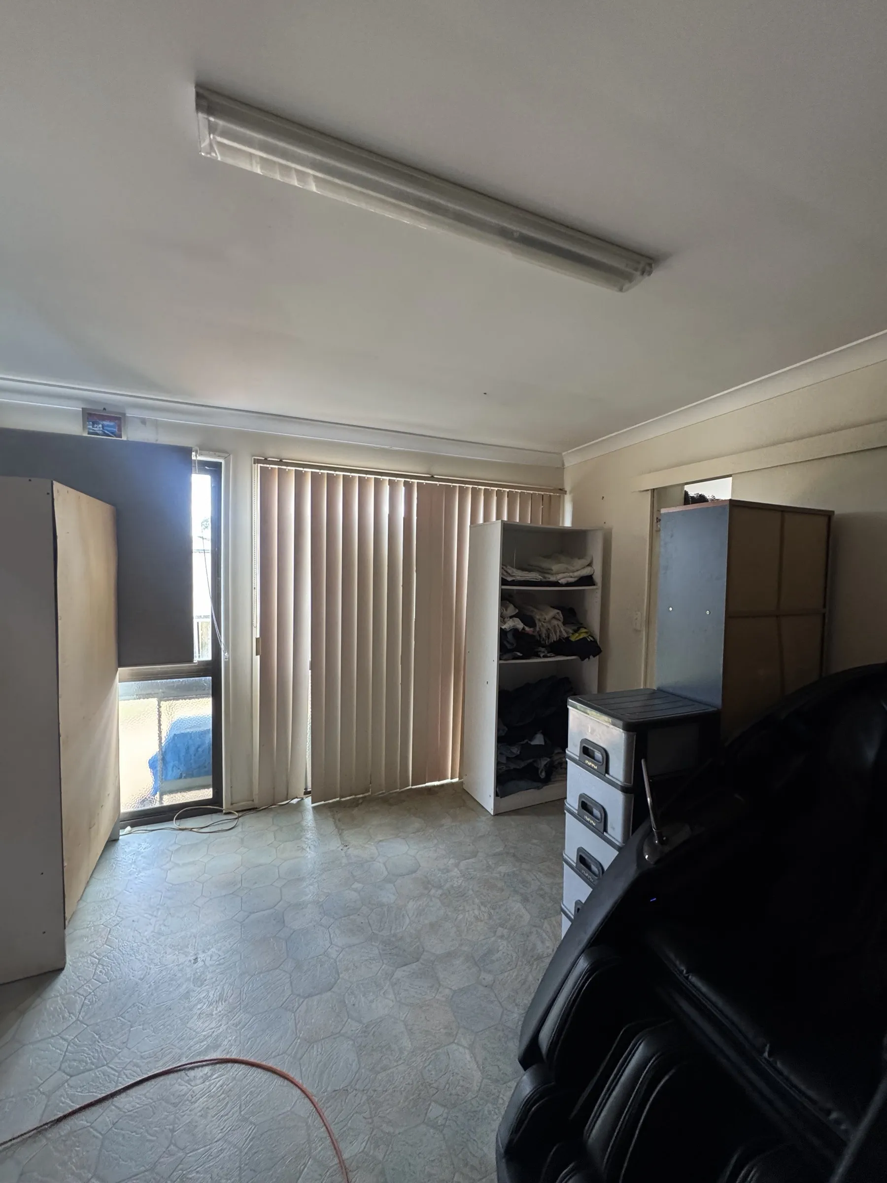 Before: interior room showing old vinyl floor coverings and venetian blinds, as it appeared prior to the flooring and interior upgrade works
