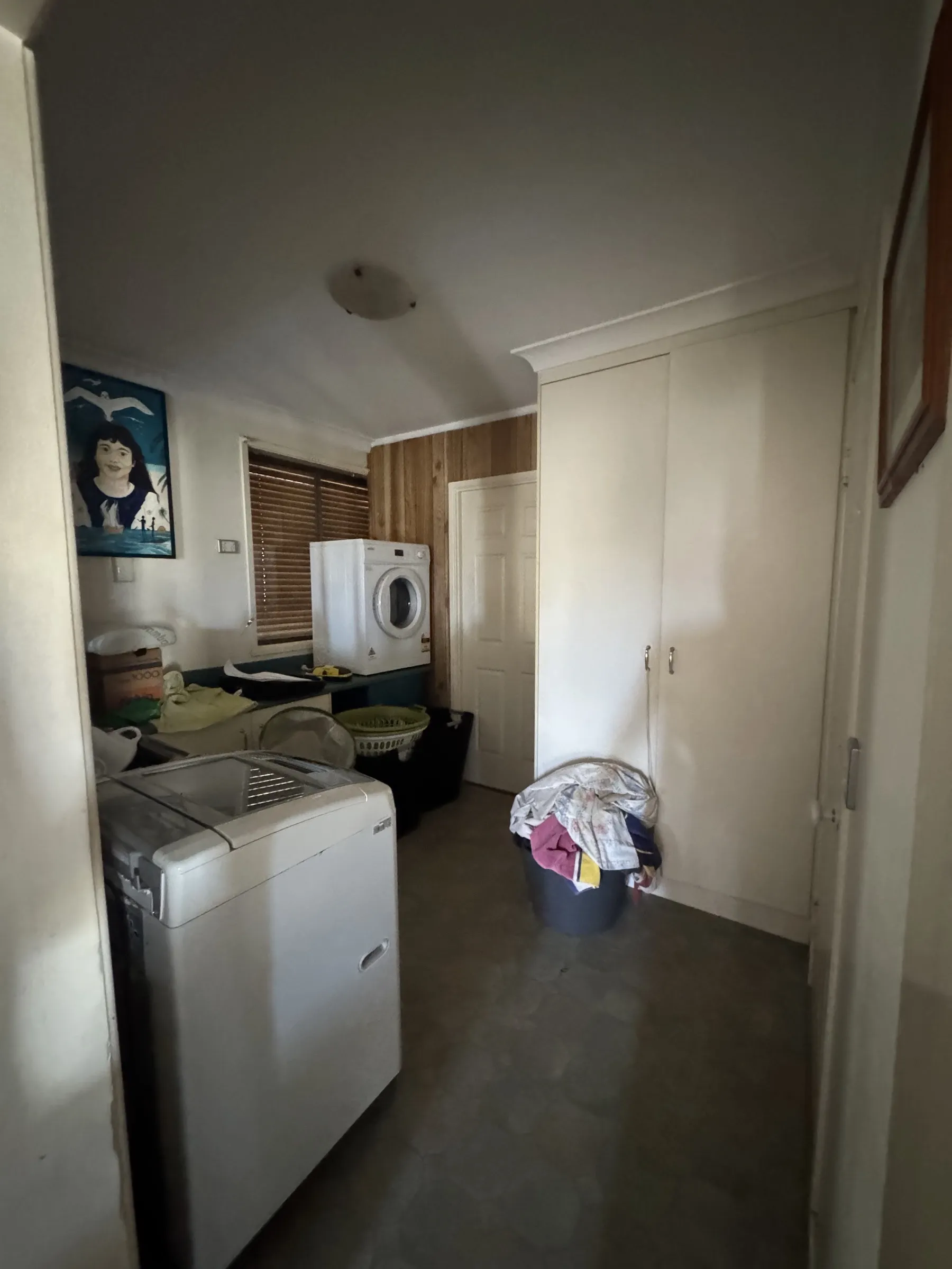 Before: cluttered laundry and utility area with original fittings, brick wall feature, and older appliances prior to the house tidy and reorganisation