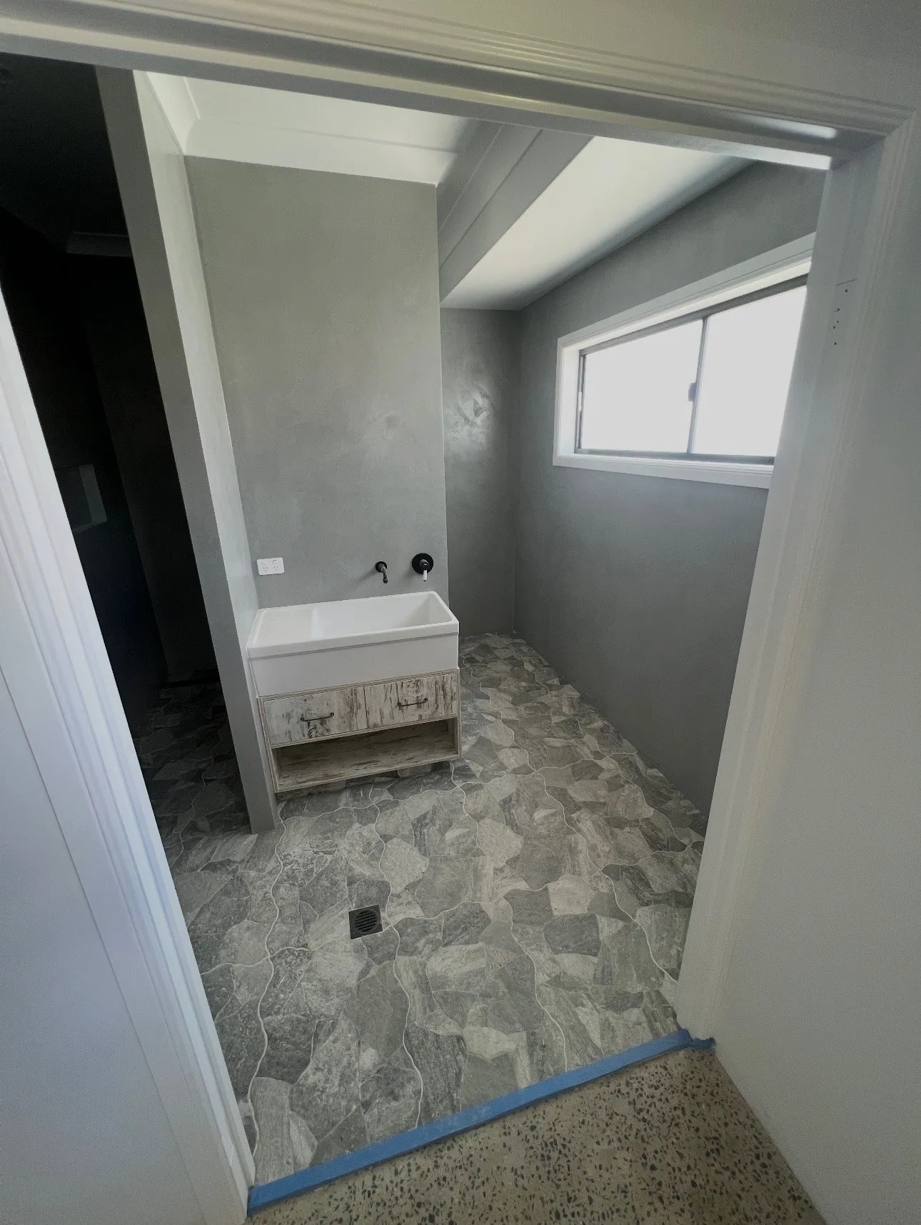A finished bathroom with a marble-look micro cement floor and freestanding bath